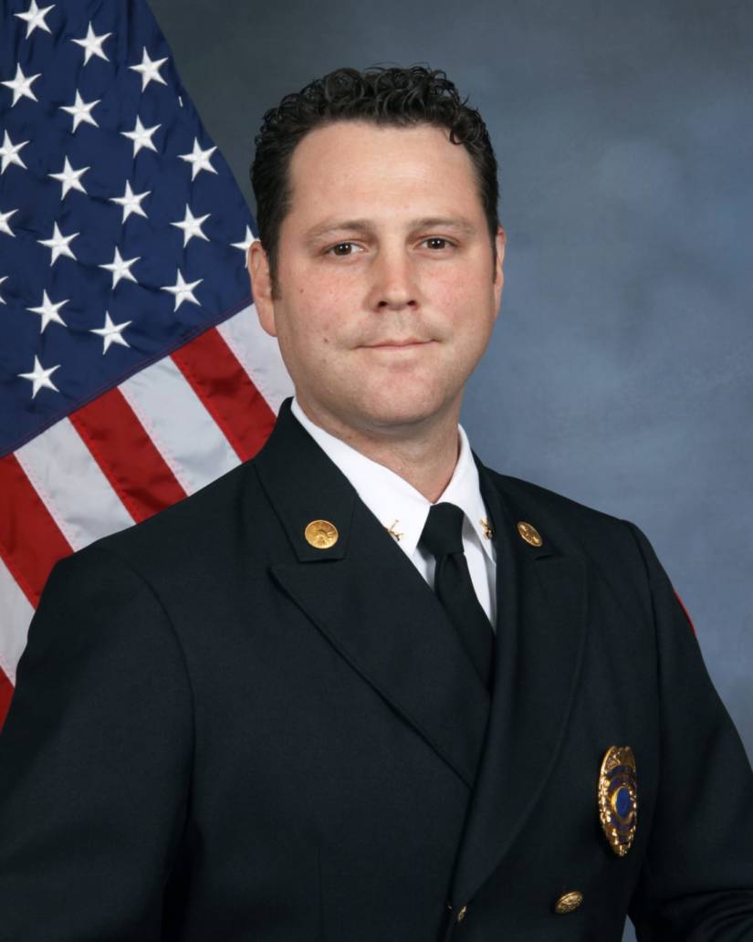 Man in uniform in front of U.S. flag