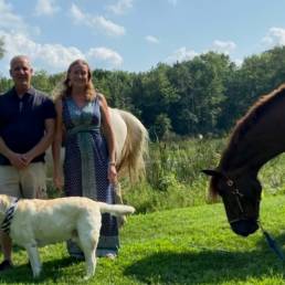 Man and woman with their dog and two horses